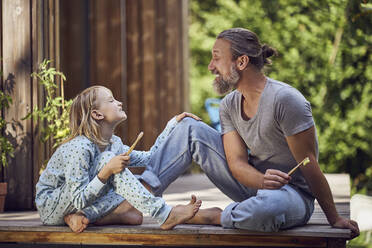 Vater und Tochter zeigen sich gegenseitig die Zähne, während sie im Hof sitzen - MCF01464