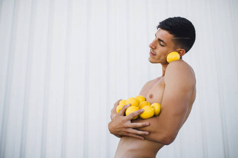Man holding lemon while standing against wall stock photo