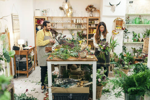 Man and woman working while standing at flower shop - MRRF00404