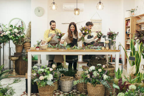 Floristenteam beim Arrangieren von Blumen und Pflanzen in einem Blumenladen - MRRF00405