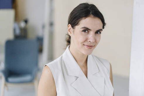 Smiling woman standing at office - KNSF08432