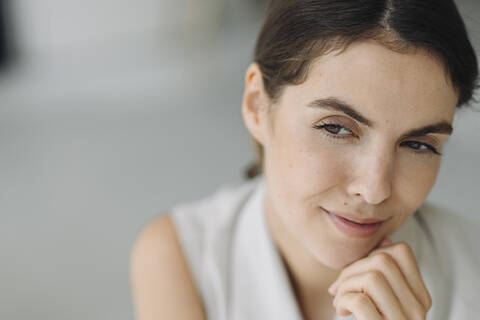 Young woman with hand on chin day dreaming at office stock photo