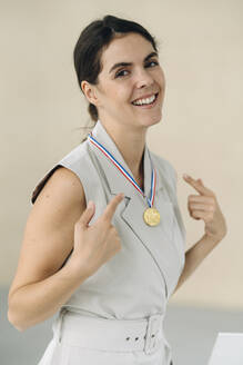 Geschäftsfrau zeigt Medaille, während sie im Büro steht - KNSF08493
