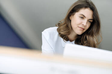 Geschäftsfrau im Stehen bei der Arbeit am Laptop im Büro - KNSF08497