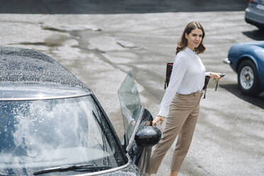 Geschäftsfrau beim Öffnen der Autotür auf einem Parkplatz - KNSF08515
