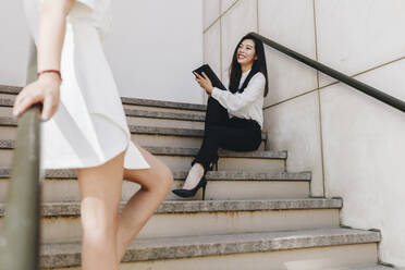 Geschäftsfrau steht neben einem lächelnden Mitarbeiter auf einer Treppe - MRRF00415