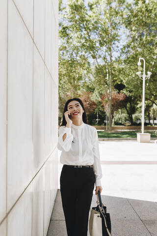 Smiling female entrepreneur taking on smart phone in city stock photo