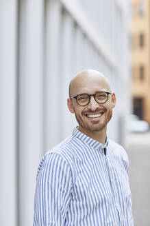 Smiling mid adult man wearing striped shirt while standing on street - MCF01500