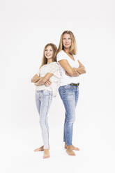 Mutter und Tochter mit verschränkten Armen stehen Rücken an Rücken vor weißem Hintergrund - SDAHF00959