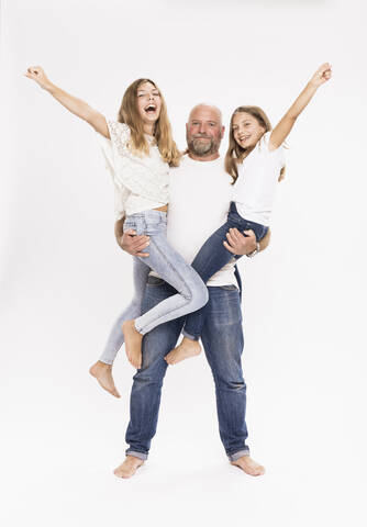Vater trägt fröhliche Töchter, während er vor einem weißen Hintergrund steht, lizenzfreies Stockfoto
