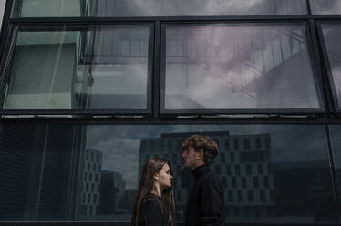 Young couple with face to face standing by building in city - OGF00548