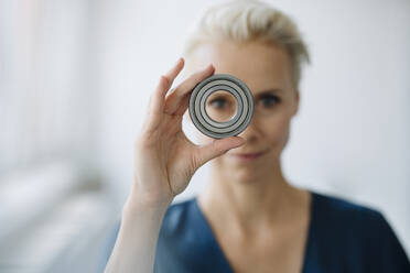Close-up of businesswoman looking through object in office - KNSF08597