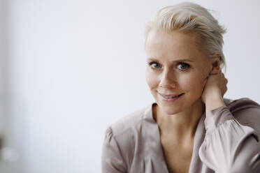 Close-up of confident businesswoman against white wall in office - KNSF08644