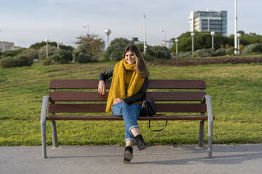 Young woman sitting on bench in park - AFVF07235