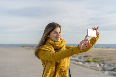 Lächelnde Frau, die mit ihrem Handy fotografiert und in den Himmel schaut - AFVF07244