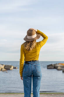 Junge Frau mit erhobenen Armen und Sonnenhut am Meer - AFVF07249