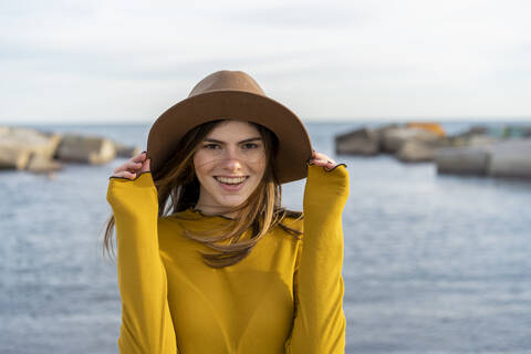 Smiling woman wearing sun hat against sea stock photo
