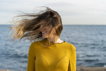 Glückliche Frau mit zerzaustem Haar, die sich am Meer erfreut - AFVF07259