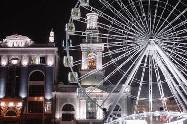 Beleuchtetes Riesenrad gegen Gebäude in nächtlicher Winterstadt - CAVF88770