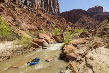 Frau paddelt mit dem Packraft auf eine kleine Stromschnelle auf dem Escalante River, Utah - CAVF88771