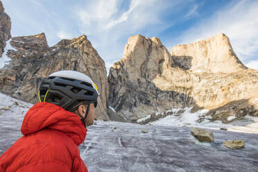 Climber wearing helmet looks up at Mount Asgard - CAVF88783