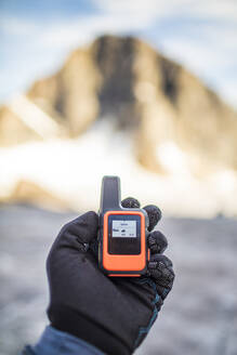 Mountaineer hält Mini-GPS-Gerät mit Wettervorhersage in der Hand. - CAVF88791