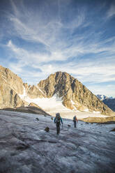 Zwei Männer überqueren einen Gletscher über einen hohen Bergpass. - CAVF88796