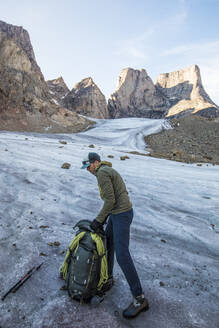 Rucksacktourist packt seine Tasche auf dem Gletscher unterhalb des Mount Asgard. - CAVF88800