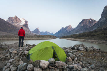 Bergsteiger genießt den Blick auf den Summit Lake von seinem Zeltplatz am Akshayak Pass - CAVF88817