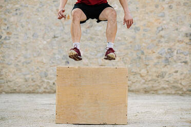 Ein Mann übt Crossfit und springt in eine plyometrische Box. - CAVF88825