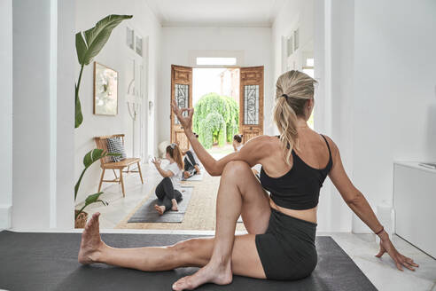 Weibliche Lehrerin leitet Frauen in einem Yogastudio bei ihren Übungen an - VEGF02896