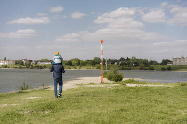 Father carrying daughter on shoulder while looking at view of Rhine river - GUSF04444