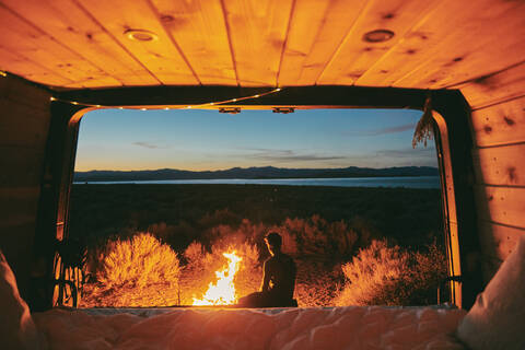 Young man by campfire in Mono Lake at night in northern California. stock photo