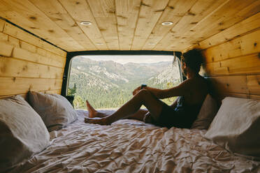 Young man on bed of camper van watching views of Yosemite Park. - CAVF88876