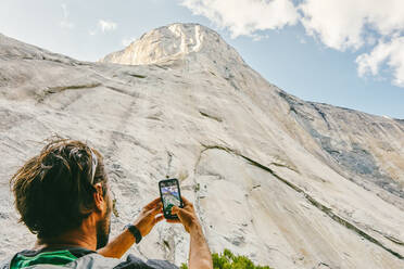 Young man taking picture of El Capitan Mountain in Yosemite Park. - CAVF88879