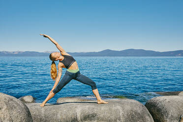 Young woman practicing yoga on Lake Tahoe in northern California. - CAVF88890
