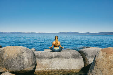 Young woman practicing yoga on Lake Tahoe in northern California. - CAVF88891