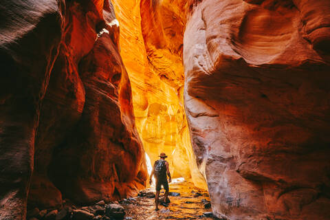 Young man wearing a hat, exploring a slot canyon in Kanarra Fall, Utah stock photo