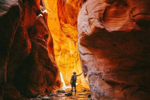 Young man wearing a hat, exploring a slot canyon in Kanarra Fall, Utah - CAVF88908