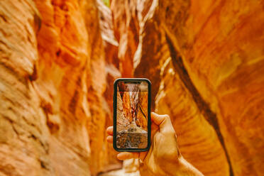 Young man's hand taking picture of slot canyons in Kanarra Falls - CAVF88909