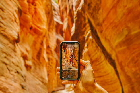 Young man's hand taking picture of slot canyons in Kanarra Falls - CAVF88909