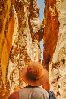 Junger Mann mit Hut, der einen Slot Canyon in Kanarra Fall, Utah, erkundet. - CAVF88910