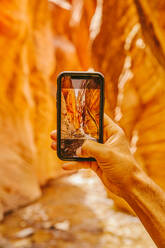 Die Hand eines jungen Mannes beim Fotografieren der Slot Canyons in Kanarra Falls - CAVF88911