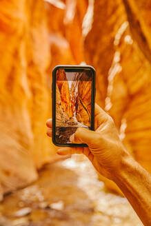 Young man's hand taking picture of slot canyons in Kanarra Falls - CAVF88911