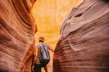 Young man exploring narrow slot canyons in Escalante, during summer - CAVF88915