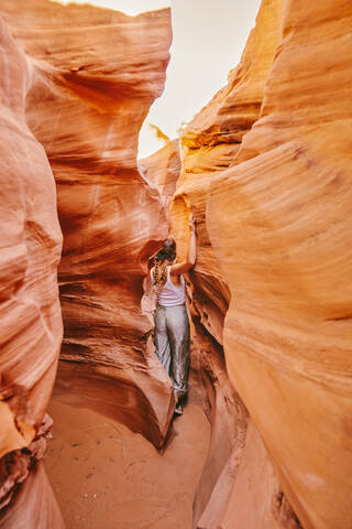 Young woman exploring narrow slot canyons in Escalante, during summer stock photo