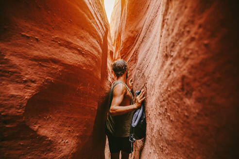 Young man exploring narrow slot canyons in Escalante, during summer - CAVF88919
