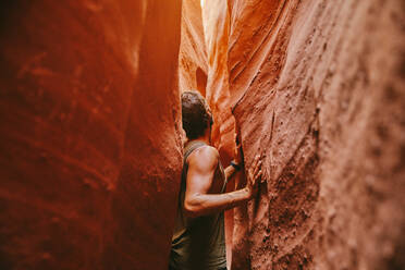 Young man exploring narrow slot canyons in Escalante, during summer - CAVF88920