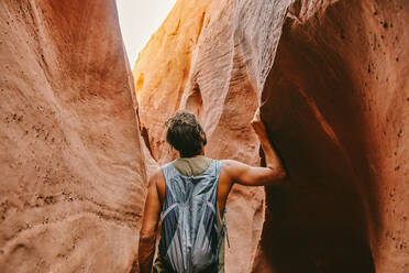 Young man exploring narrow slot canyons in Escalante, during summer - CAVF88924