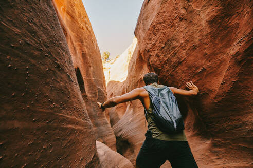 Young man exploring narrow slot canyons in Escalante, during summer - CAVF88925